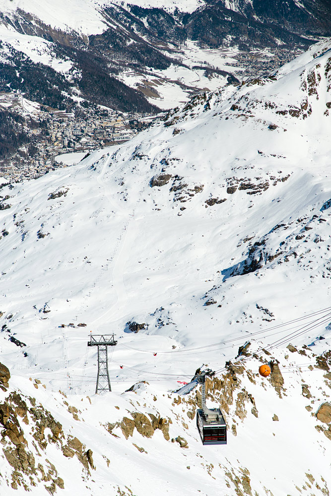 Takana näkyvästä St. Moritzin kylästä tarvitaan ensin auto- tai bussisiirtymä Corvatsch -hiihtoalueen ala-asemalle ja sieltä kaksiosainen kabiininousu tänne. Ylhäällä kannattaa sijoittaa hetki laskuaikaa maisemien ihailuun.